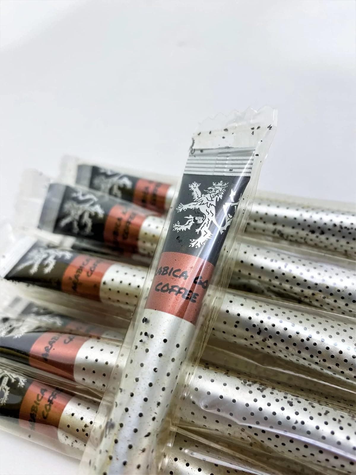 Arabica Gold Coffee sticks in their individual wrappers on a plain background